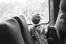 child in a conductor hat looking out a train window 
