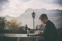 a man reading a Bible at an outdoor table 