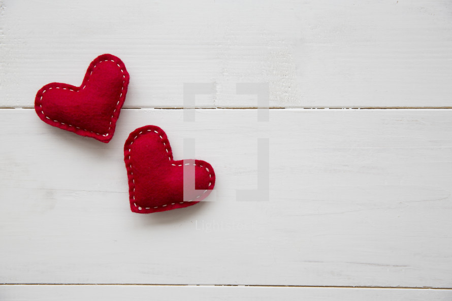 red felt hearts on a white wood table.