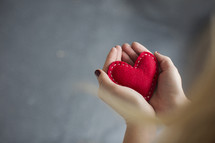 woman holding a red felt heart 