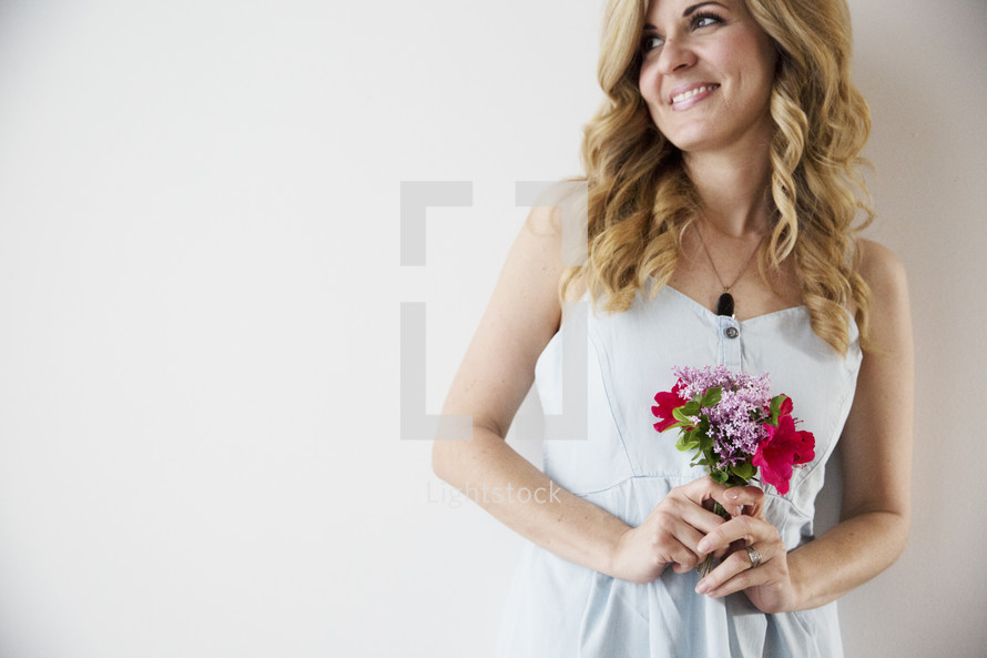 A woman in a white dress holding a bouquet of flowers.