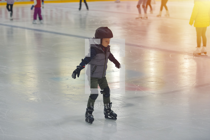 child ice skating with a helmet on