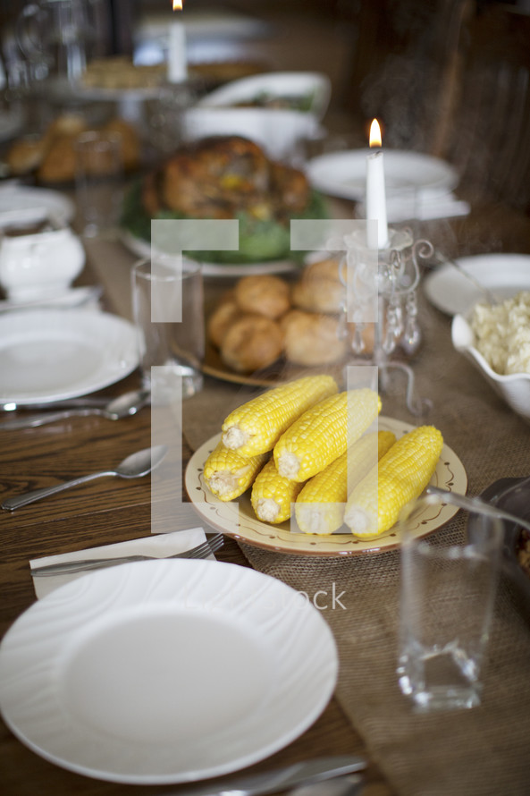 steaming hot corn and turkey on a table set for Thanksgiving dinner 