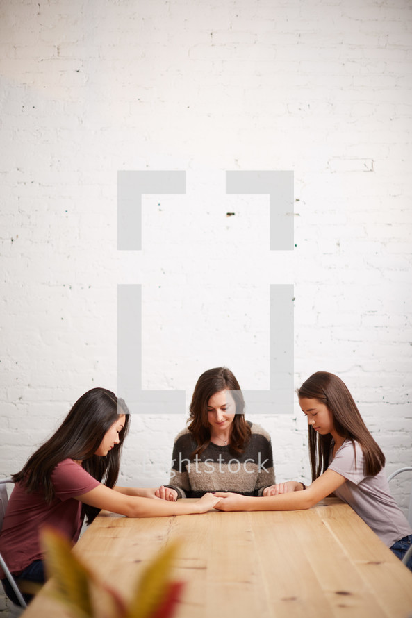 mother and daughters praying together 