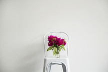 fuchsia flower in a vase on a white chair 