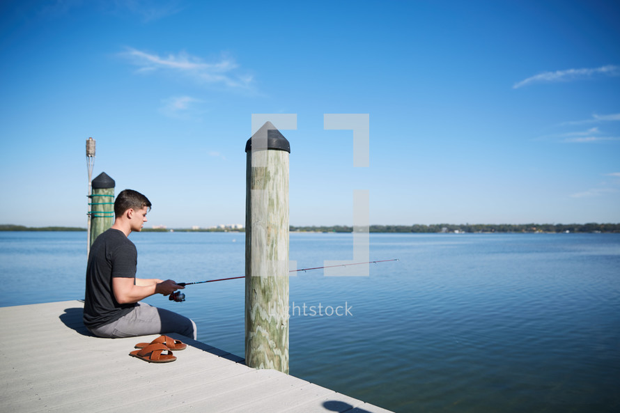 a man sitting and fishing on a pier 