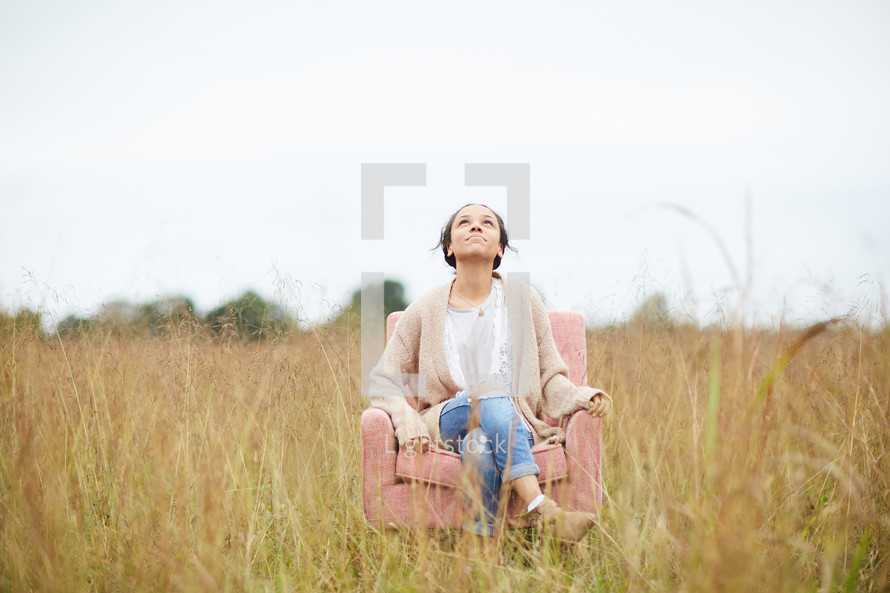 a woman sitting in a chair in a field 