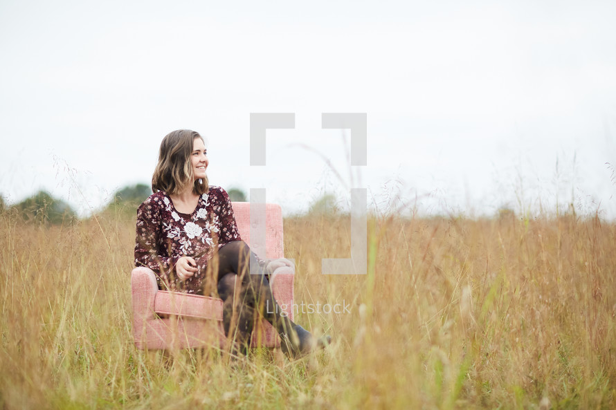 a young woman sitting in a chair in a field 