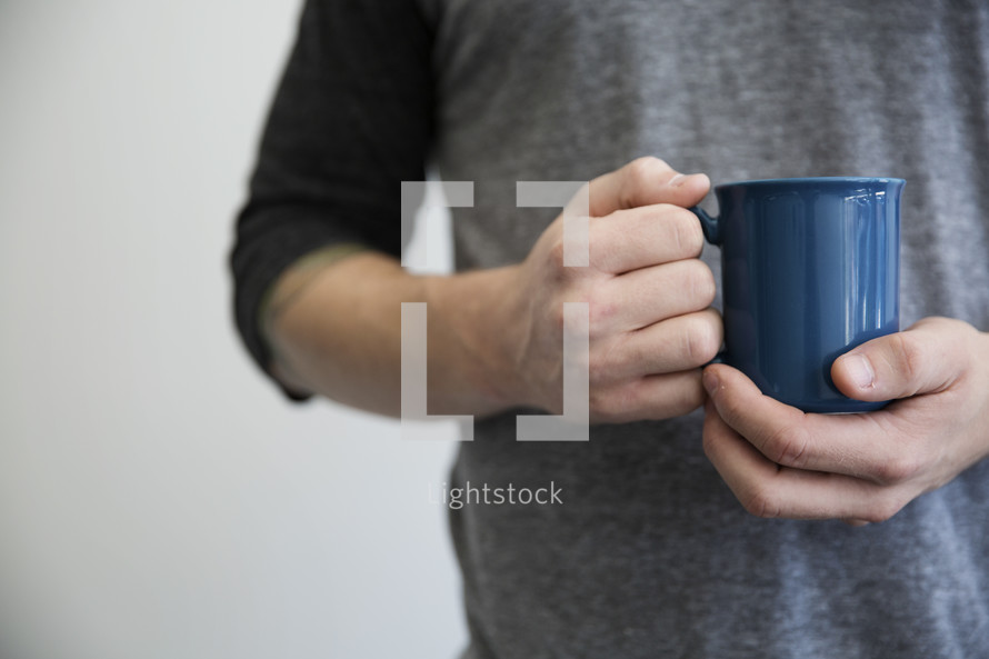 A man holding a blue coffee cup.