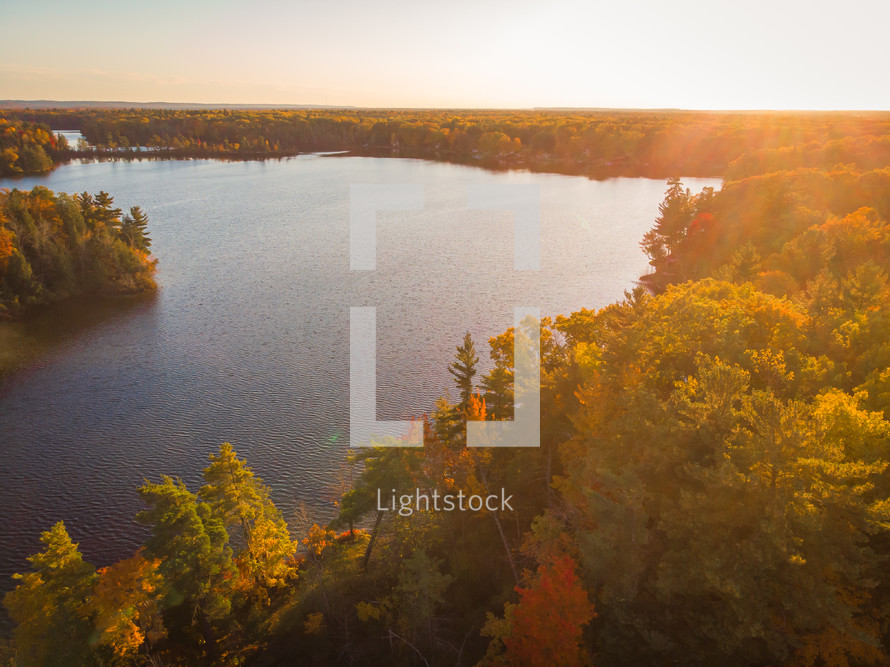 aerial view over lake and forest in fall at sunset 