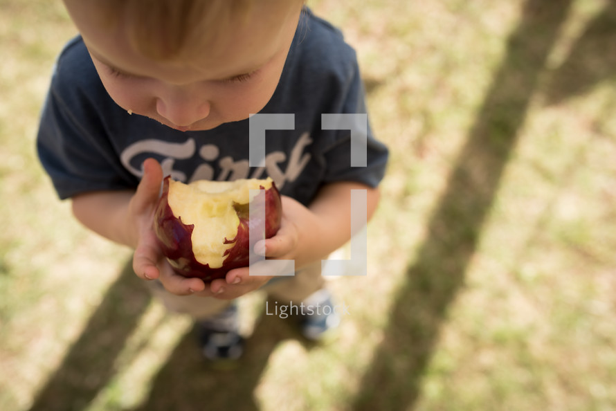 a toddler boy biting an apple 