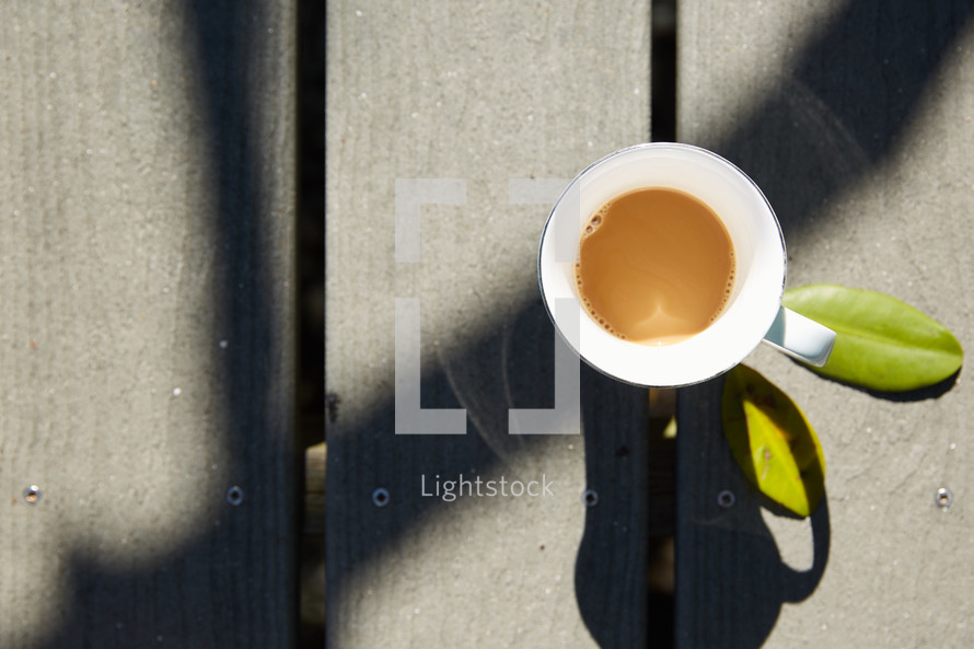 overhead view of a coffee mug on a deck 