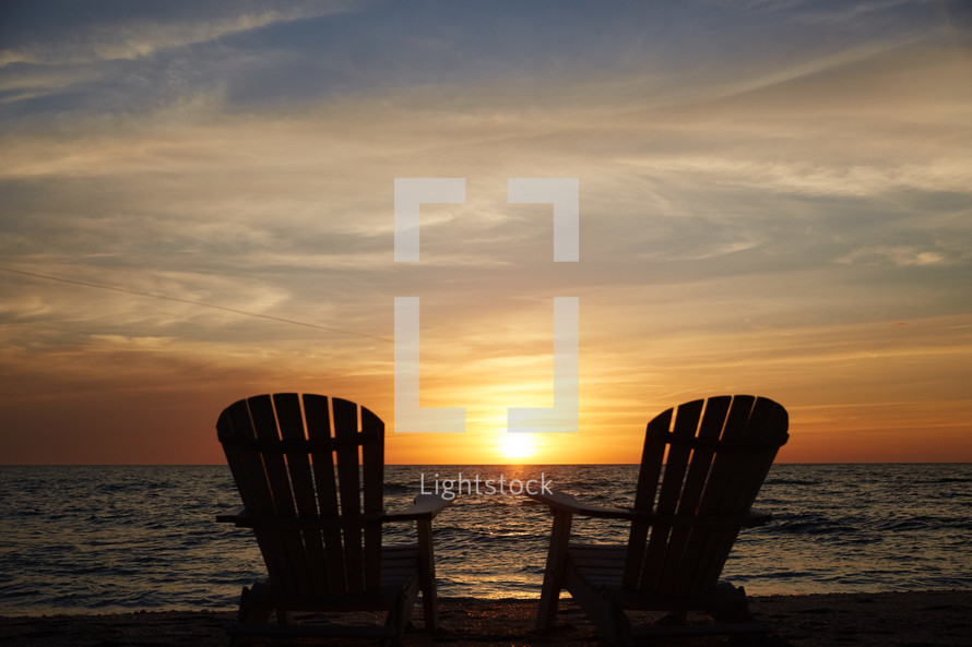 pair of adirondack chairs on a beach 