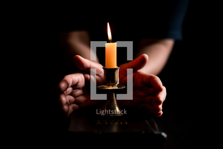 Bible and candlelight with praying hands