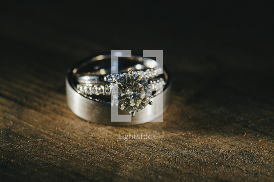 wedding band and engagement ring on a wood table