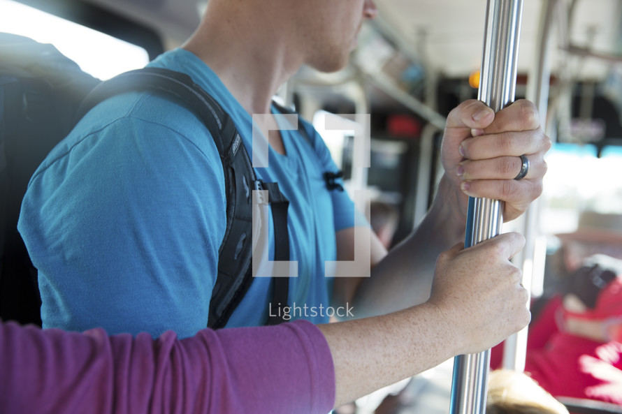 people holding onto a pole riding a city bus.
