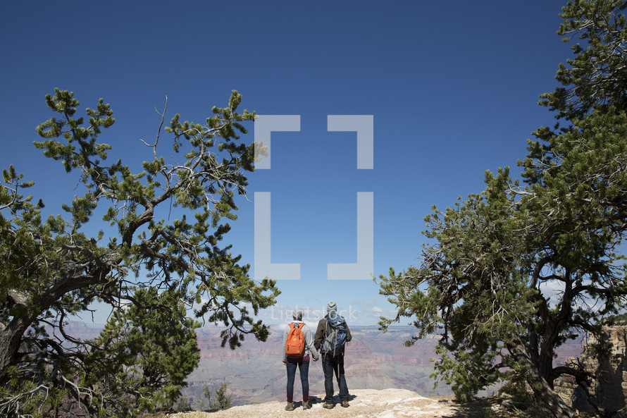 couple standing on a mountaintop with backpacks 