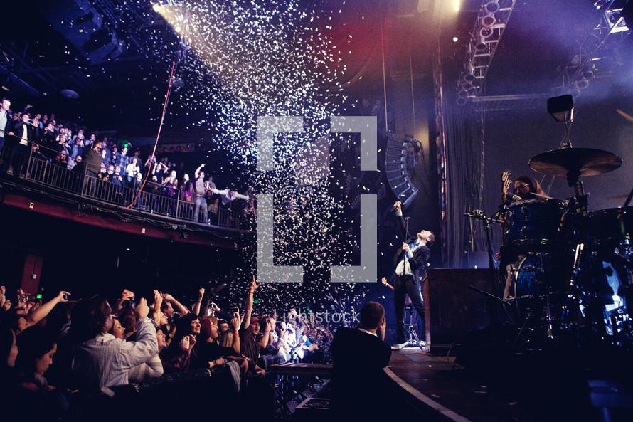 confetti falling on musicians on stage and an audience at a concert
