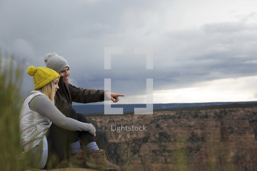 couple sitting on a mountaintop looking out