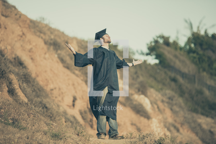 graduate with his hands raised in worship