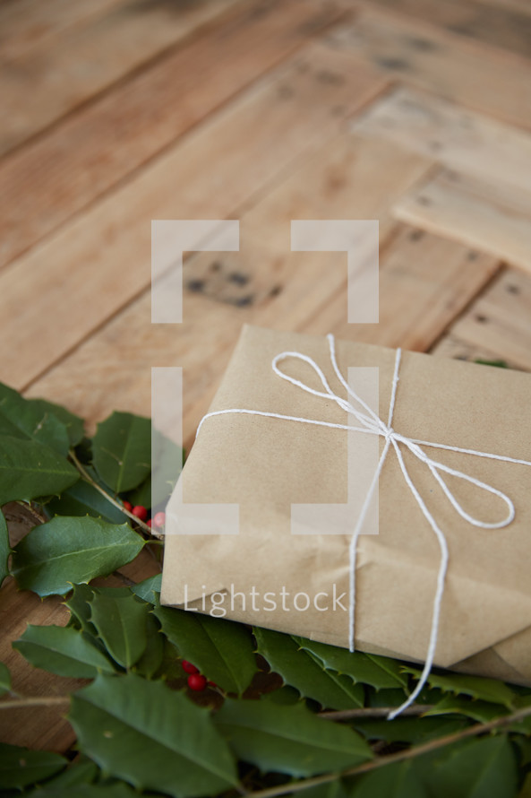 holly and gift on a white wood background 