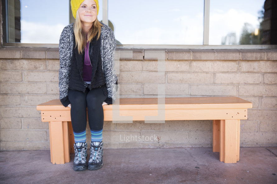woman waiting at a bus stop bench 
