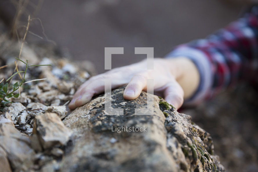 hand reaching to grab onto a rock 