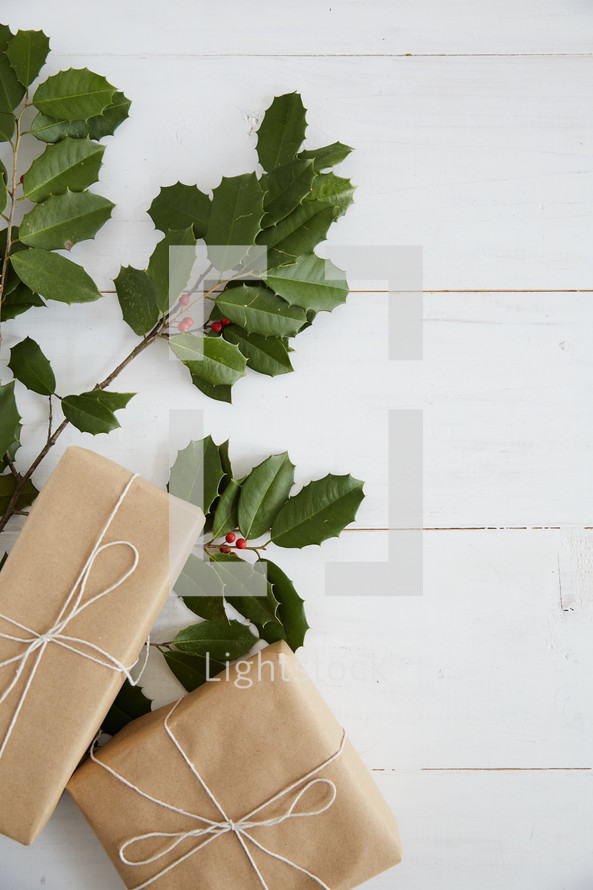 holly and gifts on a white wood background 