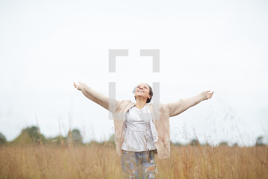 a woman with open arms standing in a field 