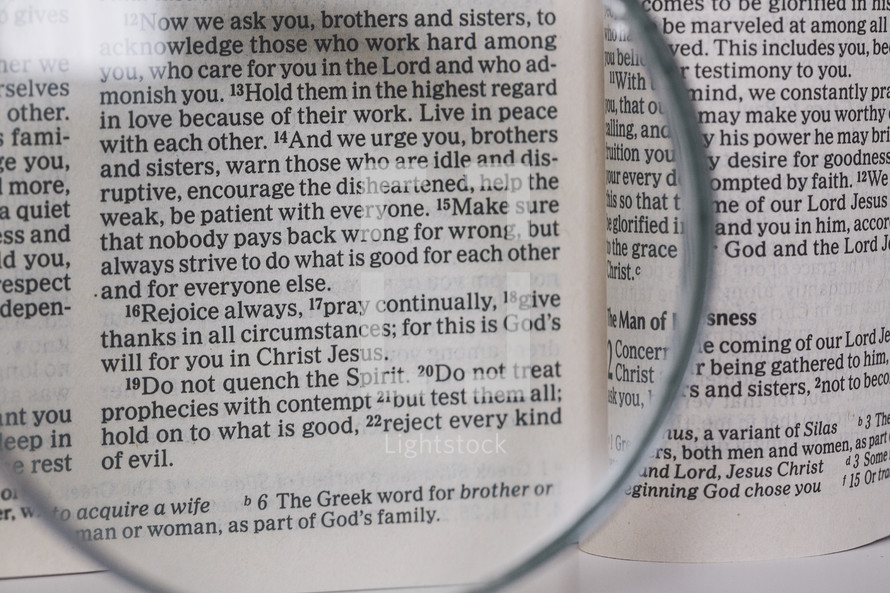 magnifying glass over pages of a Bible 