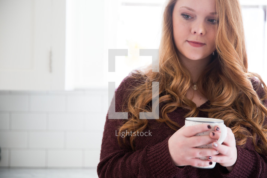 a woman holding a mug of coffee thinking 