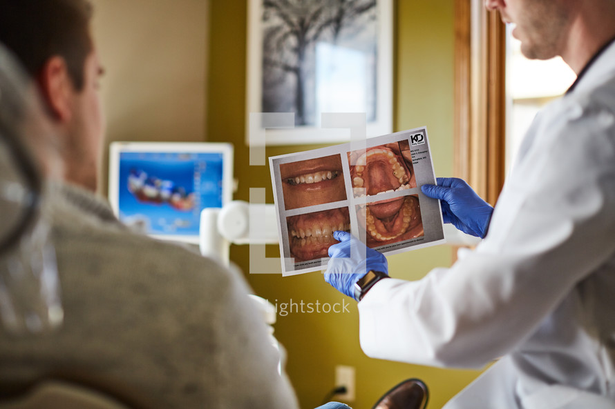 a dentist looking at digital scans of teeth and talking to his patient 