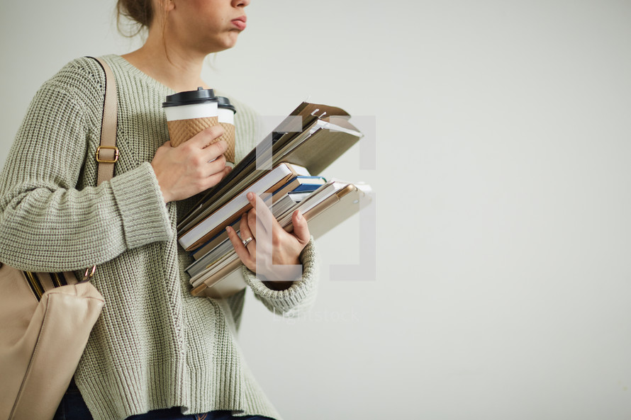 a student juggling a coffee cup and books 