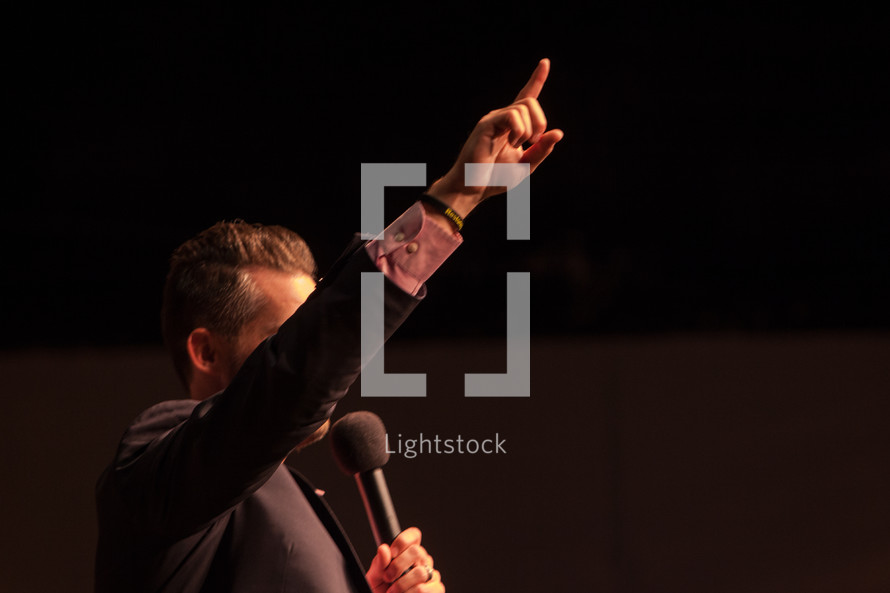 a preacher with a raised hand holding a microphone 