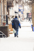 a man walking on a sidewalk in the snow 