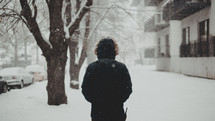 a man in a winter coat standing outdoors in snow 
