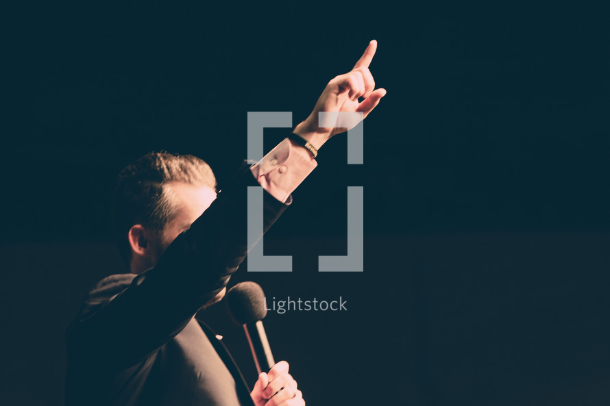 a preacher holding a microphone with a raised hands 