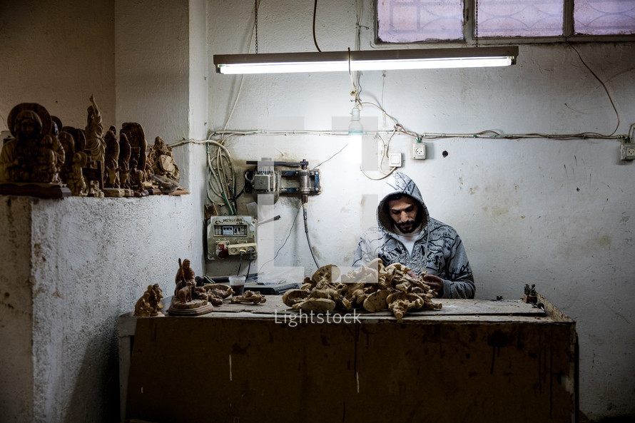 a man carving olive wood in the holy land 