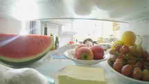 POV shot from inside a refrigerator of little girl opening the door and taking out food