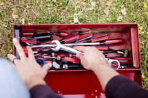 a man sorting through a toolbox 