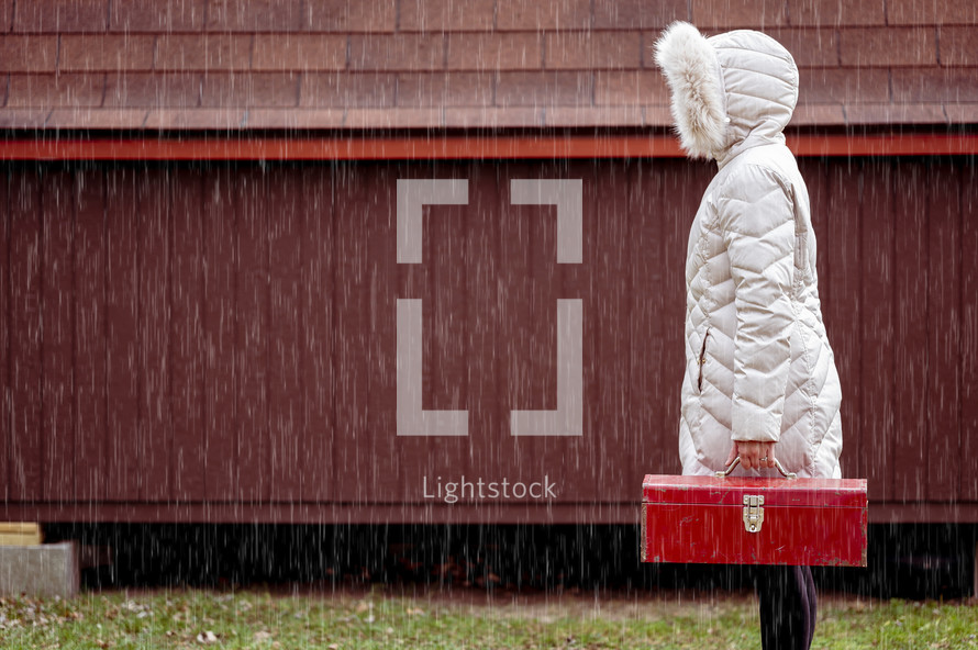 a woman holding a toolbox in the rain 
