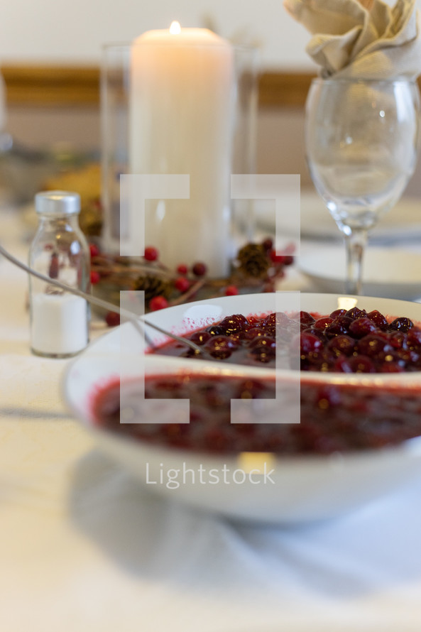 bowl of cranberry sauce on a table set for Thanksgiving 