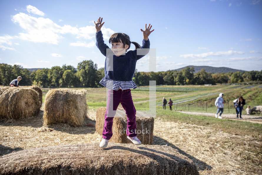 Little girls jumping on the hay