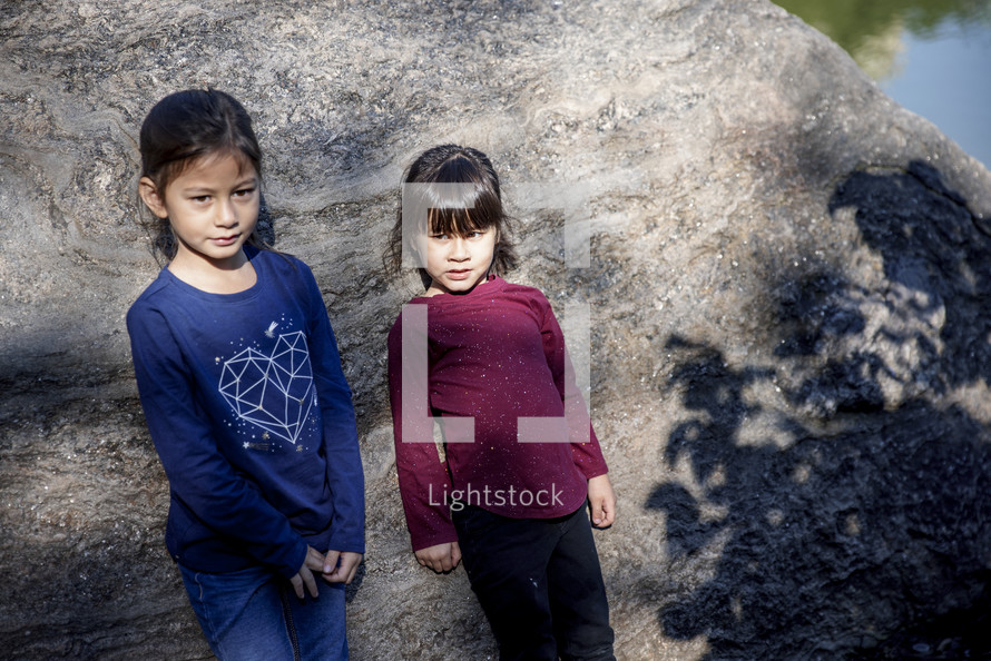 Little girls standing in front of a rock