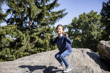 Little girl playing on a rock