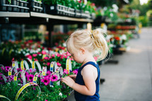 girl child picking out flowers in a garden center 