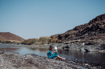 Girl holding a baby boy at Wadi Al Khoudh, a popular wadi located next to the old Al Khoudh Village in Muscat, Oman.
