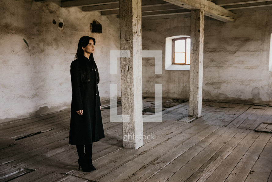 Woman in black standing in old building