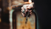 tattooed hands holding a necklace 