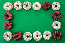 Christmas donuts frame on green 